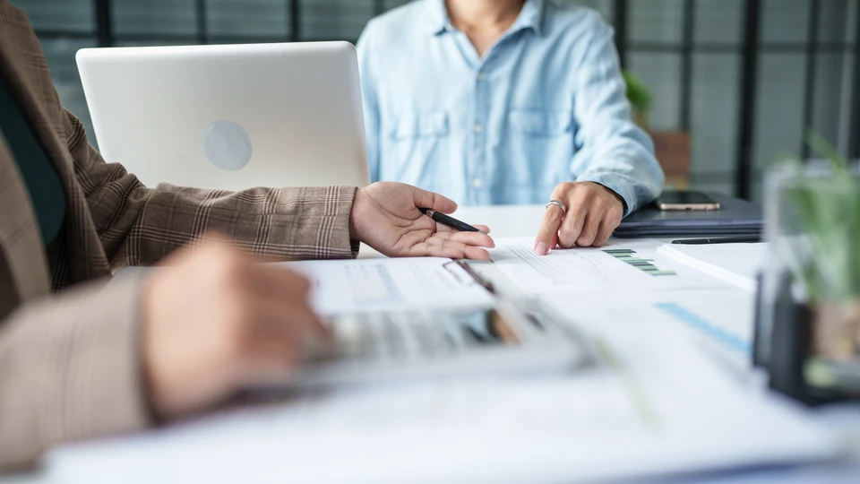 Équipe de quatre professionnels collaborant dans bureau moderne lumineux, analysant données sur ordinateur portable et documents