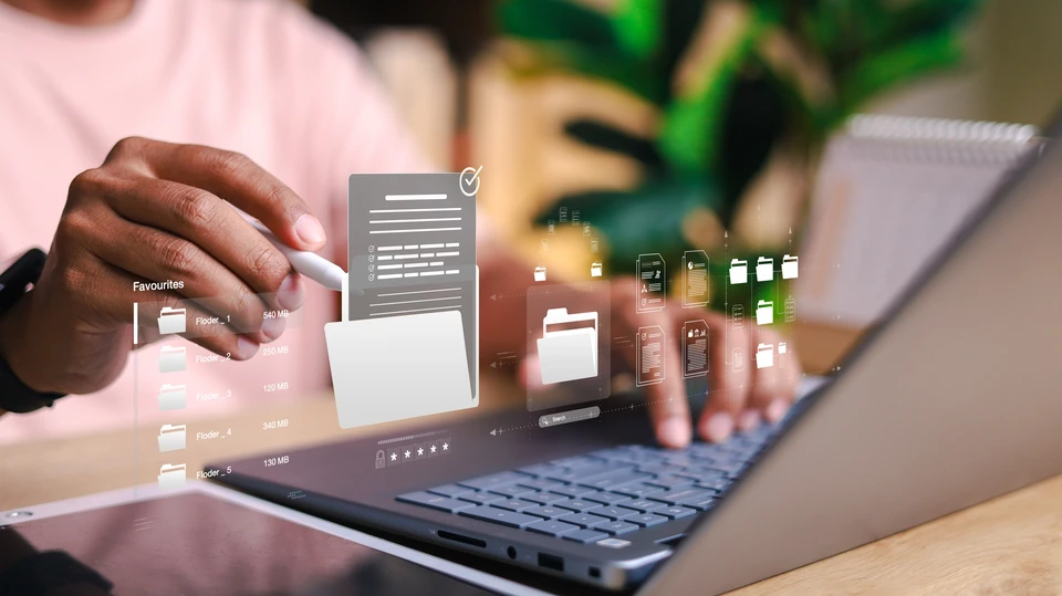 Deux femmes collaborent dans un bureau moderne, l'une tapant sur un ordinateur portable tandis que l'autre tient des documents