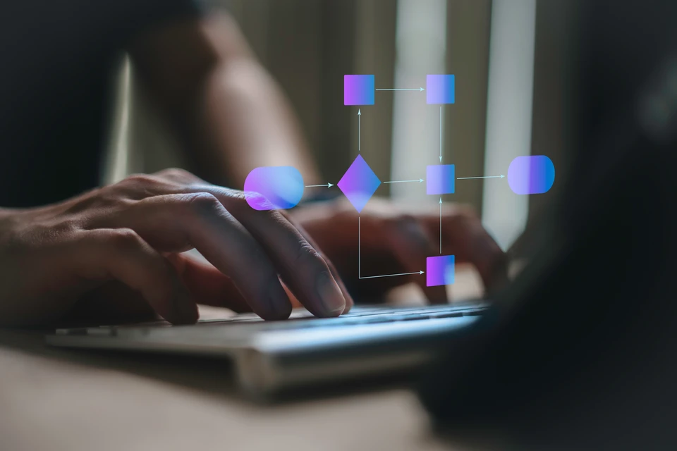 Personne en costume tenant un smartphone dans ses mains ouvertes, duquel émergent virtuellement des appareils connectés : ordinateurs portables, tablettes, moniteur d'ordinateur