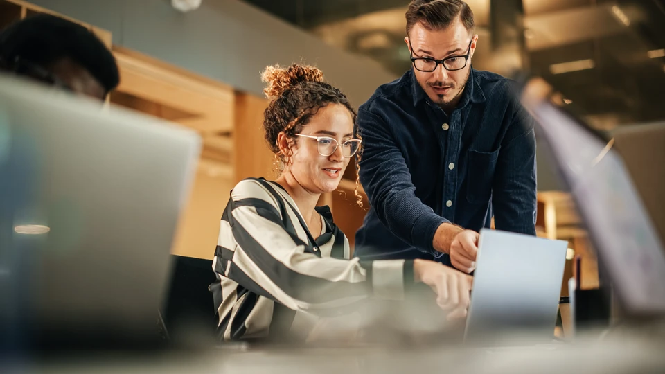 Réunion d'équipe dans bureau moderne avec six professionnels souriants autour d'une table de travail