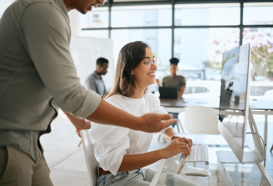 Professionnel en chemise bleue travaillant sur ordinateur portable, mains positionnées au-dessus du clavier