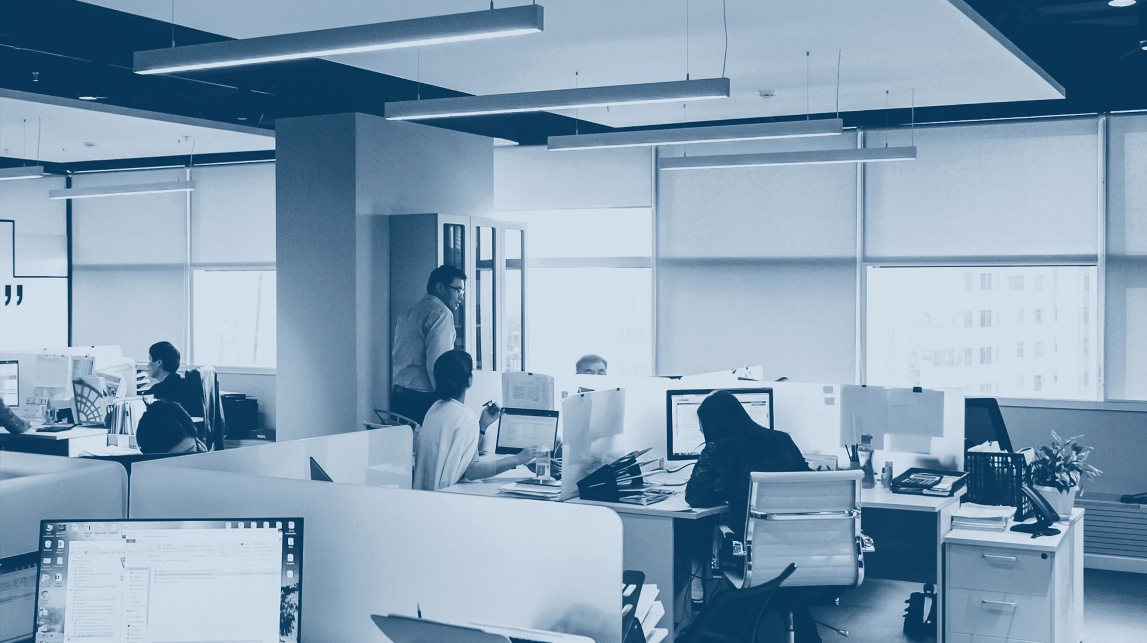 Bureau moderne en open space avec développeur travaillant sur plusieurs écrans d'ordinateur